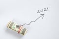 Roll with American dollars and an arrow is drawn next to it growing up to the figure 2021, financial achievements in 2021 Royalty Free Stock Photo