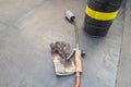 Roll of bituminous sheath, propane torch and glove resting on a bituminous membrane already laid