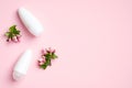 Roll-on deodorant bottles with blossom flowers on pink background. Flat lay, top view. Blank antiperspirant packaging, sweat Royalty Free Stock Photo