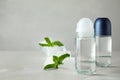 Roll-on deodorants and ice cubes with mint on grey table, space for text