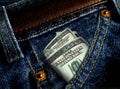 ROLL OF 100 DOLLAR BILLS INSERTED INTO BLUE JEANS POCKET CLOSEUP Royalty Free Stock Photo