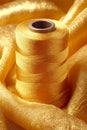 A spool of yellow thread sitting on top of a pile of fabric Royalty Free Stock Photo