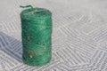 Roll of green small rope macro close up on patern striped blue and white carpet background. Royalty Free Stock Photo