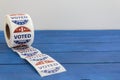 Roll of I Voted Today stickers on blue wooden table with copy space. US presidential election concept