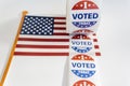 Roll of I Voted Today stickers and USA flag on white background. US presidential election concept