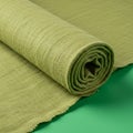 A roll of light green fabric, placed on a matching green surface. The material appears Royalty Free Stock Photo
