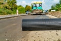 a roll of metal mesh lays on the side of the road on the background of construction equipment for road works