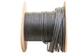 Roll of outdoor fiber optic signal shielded cable is on a white background. Wooden Coils of powerful black telecommunications wire