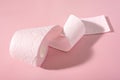 A roll of pink toilet paper on a pink background