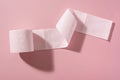A roll of pink toilet paper on a pink background
