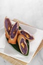 roll purple sweet potato cakes served on a wooden and leaf base with a white background