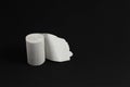 Roll of rough recycled white toilet paper stand on black background, close-up, copy space, concept of stomach problems