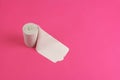 Roll of rough toilet paper stand on left side on pink background, close-up, copy space, concept of stomach problems