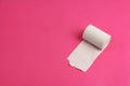 Roll of rough white toilet paper on pink background, close-up, copy space, concept of stomach problems or diarrhea