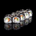 Roll Smoked California with cucumber, avocado, eel and black tobiko caviar on black with reflection. Close up. Japanese