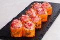 Roll with tobiko caviar and shrimp sushi cap on a black board graphite menu closeup