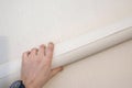Roll of wallpaper in the hand of a worker on a wall background. Apartment renovation, construction work. Close-up Royalty Free Stock Photo