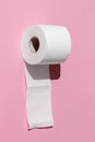 Roll of a white toilet paper isolated on a pink background close-up. hard shadows from the sun at noon Royalty Free Stock Photo