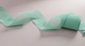 A rolled, aqua-colored ribbon extends in a wavy pattern across a smooth, light Royalty Free Stock Photo