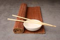 Rolled bamboo mat, chopsticks and bowl on grey table, closeup Royalty Free Stock Photo