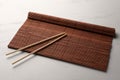 Rolled bamboo mat and chopsticks on white marble table Royalty Free Stock Photo