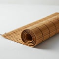 A rolled bamboo mat lies on a white surface. The mat features narrow, rectangular Royalty Free Stock Photo