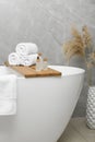 Rolled bath towels and personal care products on tub tray in bathroom Royalty Free Stock Photo