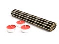 Rolled black bamboo mat and three red candles