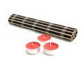 Rolled black bamboo mat and three red candles
