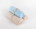 Rolled blue and beige terry towels on a white background