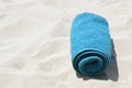 Rolled blue towel on sandy beach, space for text Royalty Free Stock Photo