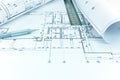 rolled blueprints, ruler and mechanic pencil on graphical architectural plan of flat