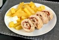 Rolled chicken fillet with prosciuto and mozzarela with pototoes on white plate on grey cloth