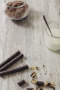 Rolled chocolate wafers, cocoa powder and a glass of milk on a rustic wooden background