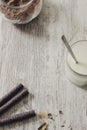 Rolled chocolate wafers, cocoa powder and a glass of milk on a rustic wooden background