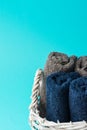 Rolled clean navy blue beige terry towels in white wicker basket turquoise wall background. Laundry ergonomic storage Royalty Free Stock Photo