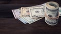Rolled hundred dollar on background series American money 5,10, 20, 50, new 100 dollar bill on brown wooden background.