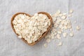 Rolled oat flakes in heart wooden bowl on linen cloth