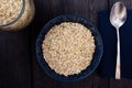 Rolled oats, healthy breakfast cereal oat flakes in bowl on dark wooden table with texture Royalty Free Stock Photo