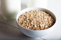 Rolled oats or oat flakes in bowl with bottle of milk on white wooden table Royalty Free Stock Photo