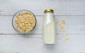 Rolled oats or oat flakes in bowl and oat milk on white wood background. Top view, horizontal. Healthy lifestyle, healthy eating, Royalty Free Stock Photo