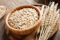 Rolled oats or oat flakes and golden wheat ears on wooden background. Royalty Free Stock Photo