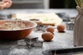 Rolled out puff pastry and molds for baking cookies, eggs, wooden rolling pin, spilled flour, a jug with ears of wheat on a black Royalty Free Stock Photo