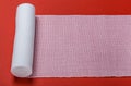 Rolled out roll of medical bandage on red background Royalty Free Stock Photo