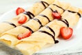 Rolled pancakes with strawberry on plate on white wooden background. Royalty Free Stock Photo