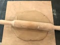 Rolled piece of pottery clay with a wooden rolling pin on a board on a black work table. Top view