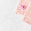 Rolled pink towel and pink orchid flower on white concrete background. Minimalist scandinavian style. SPA concept