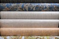 Rolled rolls of vinyl quality wallpaper in a building supermarket, store, market. Dense gray, beige, patterned wallpaper for the