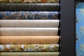 Rolled rolls of vinyl quality wallpaper in a building supermarket, store, market. Dense gray, beige, patterned wallpaper on wall,