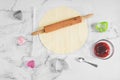 Rolled round shortbread dough with a wooden rolling pin,molds heart strawberry jam on a marble table. Royalty Free Stock Photo